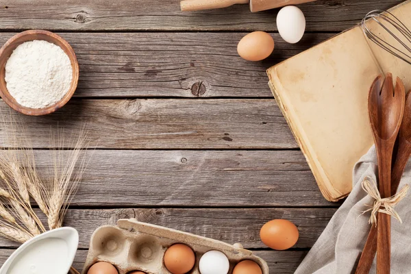 Köksbord med kokbok, köksredskap och ingredienser — Stockfoto