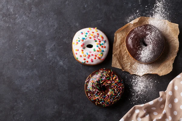 Donuts coloridos na mesa de pedra — Fotografia de Stock