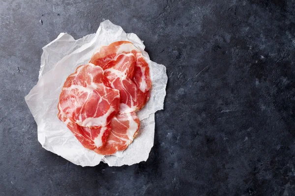 Slices of prosciutto on paper — Stock Photo, Image