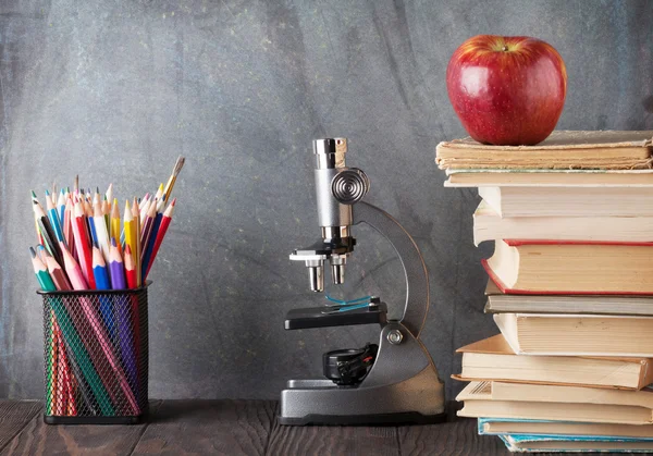 Microscoop, potloden, boeken en apple — Stockfoto