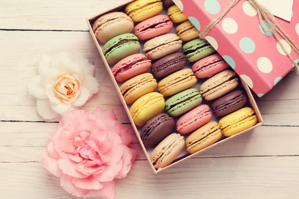 Macaroons coloridos em caixa de presente e rosas — Fotografia de Stock