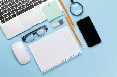 İş masası iş yeri ve ofis eşyaları mavi arka planda. Üstteki görünüm düzlüğü metin için kopyalama alanı ile yatıyordu