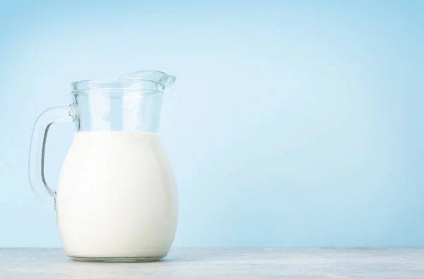 Mjölk Glaskanna Framför Blå Bakgrund Med Kopieringsutrymme — Stockfoto