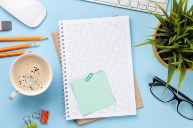 İş masası iş yeri ve ofis eşyaları mavi arka planda. Üstteki görünüm düzlüğü metin için kopyalama alanı ile yatıyordu