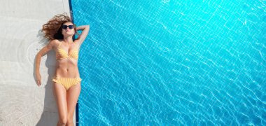 Yaz tatilinde yüzme havuzunda dinlenen bir kadın. Sıcak güneşli tatil konsepti. Üst görünüm düzlüğü kopyalama alanı ile yatıyordu