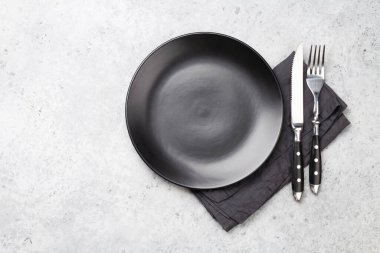 Siyah boş tabak, çatal, bıçak ve peçete. Üst görünüm düz, yemek için yer var.