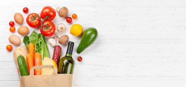 Different food in recycling paper bag on wooden table. Top view flat lay with copy space
