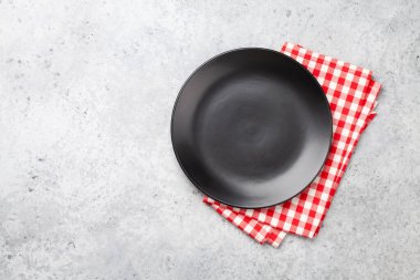 Siyah boş tabak ve kağıt peçete. Üst görünüm düz, yemek için yer var.