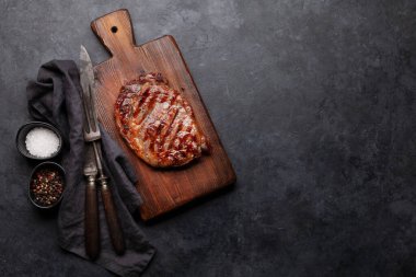 Baharatlı ızgara biftek. Kesme tahtasında. Üst görünüm düzlüğü kopyalama alanı ile yatıyordu