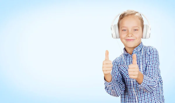 ヘッドフォンで音楽を聴き 親指を立てる少年 コピースペースを持つ色の背景に — ストック写真
