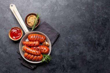 Kızartma tavasında ızgara sosis ve sos. Üst görünüm düzlüğü kopyalama alanı ile yatıyordu