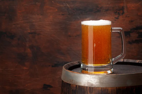 Mug of light lager beer and old wooden barrel. With copy space