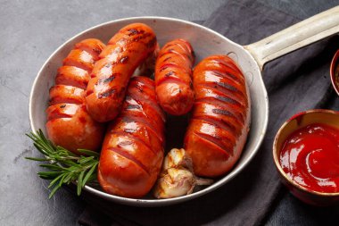 Kızartma tavasında ızgara sosis ve sos.