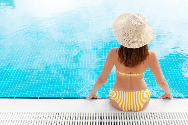Yaz tatilinde yüzme havuzunda dinlenen bir kadın. Sıcak güneşli tatil konsepti. Kopyalama alanı ile