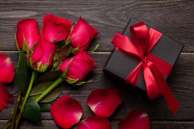 Kırmızı gül çiçekleri ve hediye kutusuyla Sevgililer Günü tebrik kartı. Üst görünüm düzlüğü