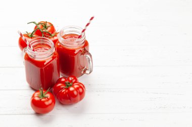 Taze domates suyu ve ahşap masada olgun domatesler. Kopyalama alanı ile