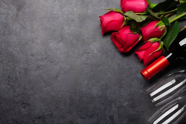 赤いバラの花の花束 ワインと石のテーブルの上にメガネを持つバレンタインデーグリーティングカード トップビューフラットレイアウトあなたの挨拶のためのスペース — ストック写真