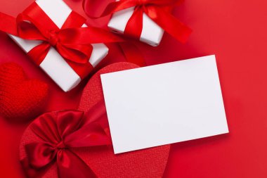 Sevgililer Günü tebrik kartı şablonu. Kırmızı arka planda hediye kutuları ve kalp şekilli dekorlar. Üst görünüm düzlüğü kopyalama alanı ile yatıyordu