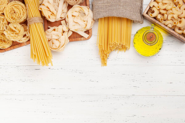 Различные виды итальянской пасты и оливкового масла на деревянном столе. Квартира с видом сверху лежала с местом для копирования