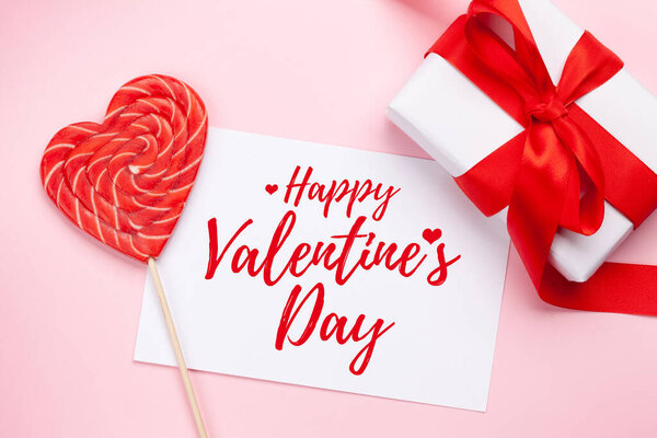 Открытки на день Святого Валентина. Подарочная коробка и сердечные конфеты леденец на розовом фоне. Квартира с видом сверху