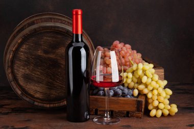 Şarap şişesi, üzüm, bir bardak kırmızı şarap ve eski ahşap fıçı. Kopyalama alanı ile