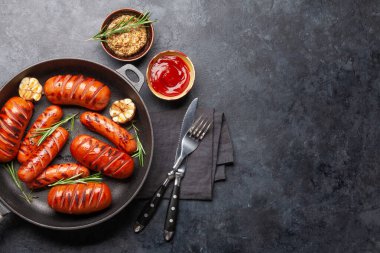 Kızartma tavasında ızgara sosis, ketçap ve hardal. Üst görünüm düzlüğü kopyalama alanı ile yatıyordu