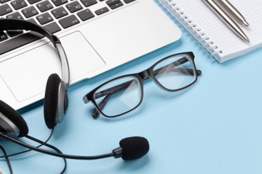 Kulaklık, gözlük ve dizüstü bilgisayarlı ofis masası. Uzak ofis ve ev konseptinden çalışma