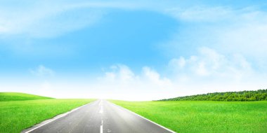 Yeşil çimlerin ve güneşli gökyüzünün içinden geçen yol. Geniş yaz manzarası