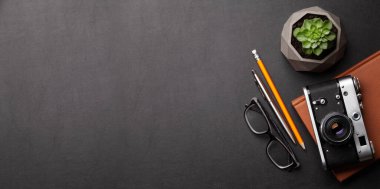 Ofis masasında malzemeler, fotoğraf makinesi ve siyah deri masanın üzerinde gözlükler. Üst görünüm düzlüğü kopyalama alanı ile yatıyordu