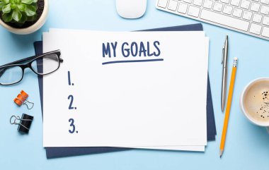 Hedef listesi şablonu, malzemeleri ve bilgisayarı olan ofis çalışma masası. Düz yatıyordu. Hedefleriniz için en üst görünüm alanı