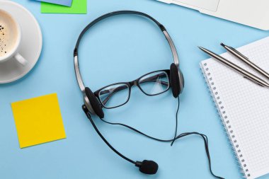 Kulaklık, bardak, kahve ve dizüstü bilgisayarlı ofis masası. Uzak ofis ve ev konseptinden çalışma