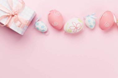 Paskalya tebrik kartı, hediye kutusu ve pembe arka planda renkli paskalya yumurtaları. Tebrik etmek için en üstteki dairede yer var.