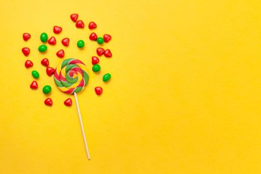 Çeşitli tatlı çeşitleri var. Sarı arka planda şeker ve lolipoplar. Üst görünüm düzlüğü kopyalama alanı ile yatıyordu