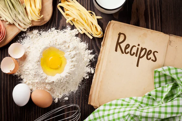 Vintage recipe cooking book, utensils and ingredients on wooden table. Top view flat lay