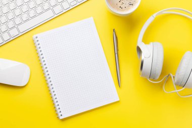 Ofis masasında malzeme, kulaklık ve boş not defteri var. Yaratıcılık ve ilham çalışması konsepti. Üst görünüm düzlüğü kopyalama alanı ile yatıyordu