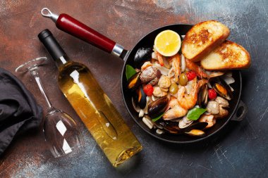 Karışık ızgara deniz ürünleri. Çeşitli kızarmış karidesler, midyeler ve tavada kabuklu deniz ürünleri ve beyaz şarap. Üst görünüm düzlüğü