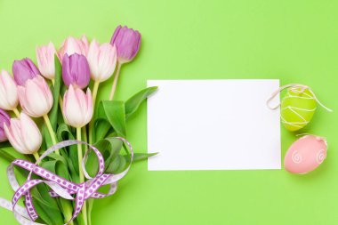 Paskalya tebrik kartı, yeşil arka planda paskalya yumurtaları ve lale çiçekleri. Üst görünüm düzlüğü kopyalama alanı ile yatıyordu