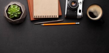 Ofis masasında malzemeler, fotoğraf makinesi ve siyah deri masanın üzerinde kahve. Üst görünüm düzlüğü kopyalama alanı ile yatıyordu