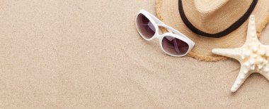 Güneş gözlüğü, şapka ve deniz yıldızıyla kumsalda seyahat etmek. Kopyalama alanı olan üst görünüm. Düz yatıyordu