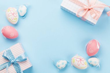 Hediye kutularıyla Paskalya tebrik kartı ve mavi arka planda renkli paskalya yumurtaları. Tebrik etmek için en üstteki dairede yer var.