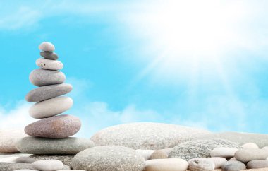 Güneşli gökyüzünün önündeki deniz taşları piramidi. Yaşam dengesi ve uyum kavramı