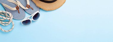 Yaz tatili eşyaları ve aksesuarları. Terlikler, güneş gözlüğü ve mavi arka planda güneş şapkası. Üst görünüm düzlüğü kopyalama alanı ile yatıyordu
