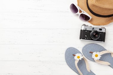 Yaz tatili eşyaları ve aksesuarları. Parmak arası terlik, güneş gözlüğü, kamera ve güneş şapkası. Üst görünüm düzlüğü kopyalama alanı ile yatıyordu