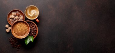 Kavrulmuş kahve çekirdekleri, öğütülmüş toz, esmer şeker ve bir fincan sıcak espresso kahvesi. Üst görünüm düzlüğü kopyalama alanı ile yatıyordu