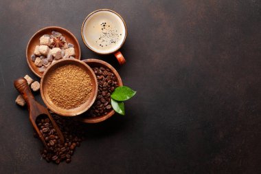 Kavrulmuş kahve çekirdekleri, öğütülmüş toz, esmer şeker ve bir fincan sıcak espresso kahvesi. Üst görünüm düzlüğü kopyalama alanı ile yatıyordu