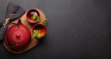 Nane ve limonlu bitki çayı. Çay fincanı ve çaydanlık taş masada. Üst görünüm düzlüğü kopyalama alanı ile yatıyordu