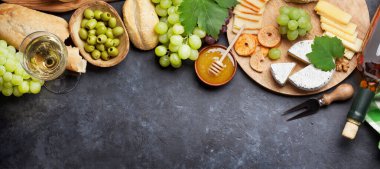 Taş masada beyaz şarap, üzüm, ekmek, bal ve peynir. Üst görünüm düzlüğü