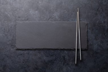 Suşin ve makin için taş tabak ve çubuk. Japon yemek menüsü arka planı. Üst görünüm düzlüğü kopyalama alanı ile yatıyordu