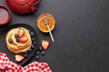 Krep ve bitki çayıyla sağlıklı bir kahvaltı. Böğürtlenli ve ballı ev yapımı Amerikan krepleri. Üst görünüm düzlüğü kopyalama alanı ile yatıyordu