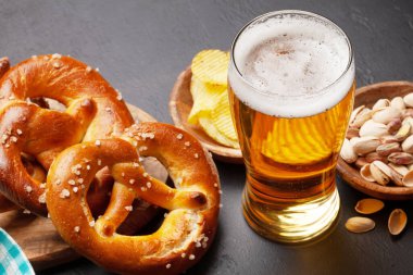 Bira bardağı, fındık, patates cipsi ve taş masada deniz tuzu ve taze pişmiş kraker. Klasik bira atıştırmalığı.